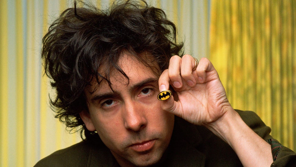 Tim Burton holds a tiny Batman pin. 