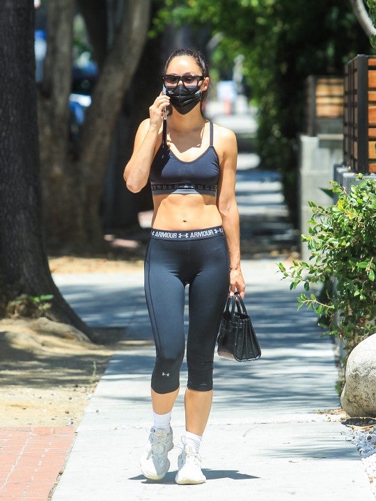 Shay Mitchell wears an oversized shirt over sports bra and leggings while  leaving a hot Pilates